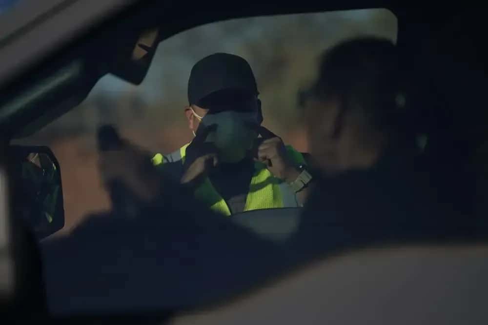 An officer with the Navajo Nation Police talks to a driver at a roadblock in Tuba City, Arizona, on the Navajo reservation on April 22, 2020. The roadblock was to inform residents of evening and weekend curfews to help control the spread of COVID-19. (AP Photo/Carolyn Kaster, File)