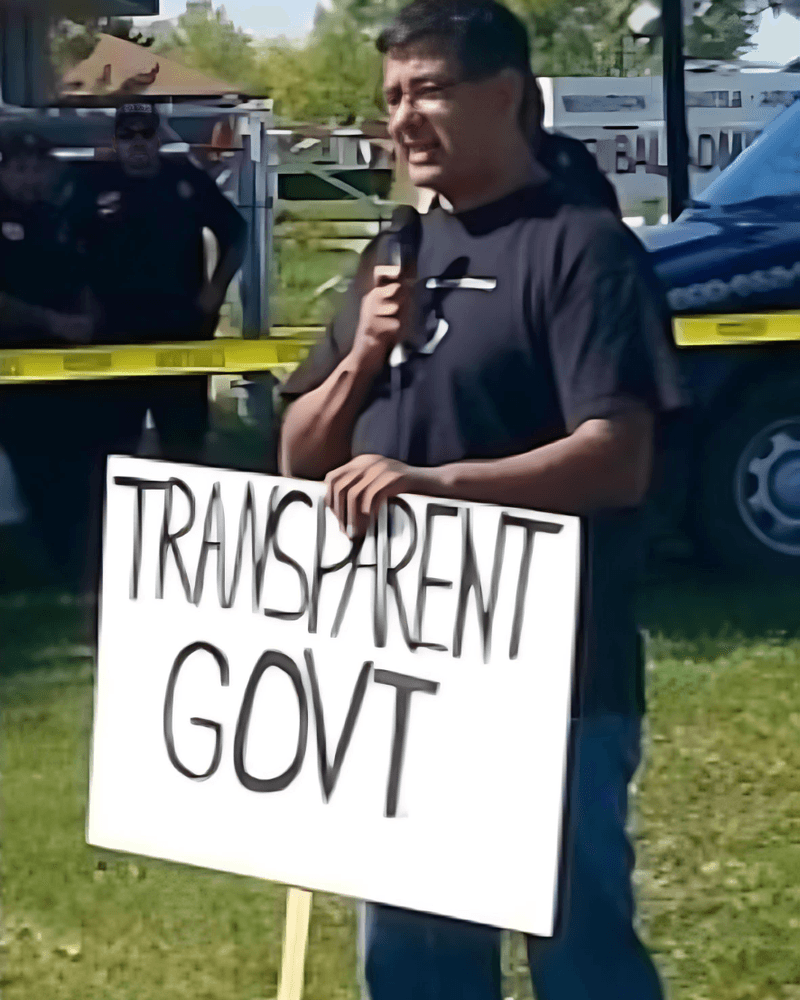 In 2014, Mark Fox holds a tribal government transparency sign as he campaigns outside the Mandan, Hidatsa and Arikara Nation tribal administration building in New Town, North Dakota.  It was his first tribal chairman campaign.