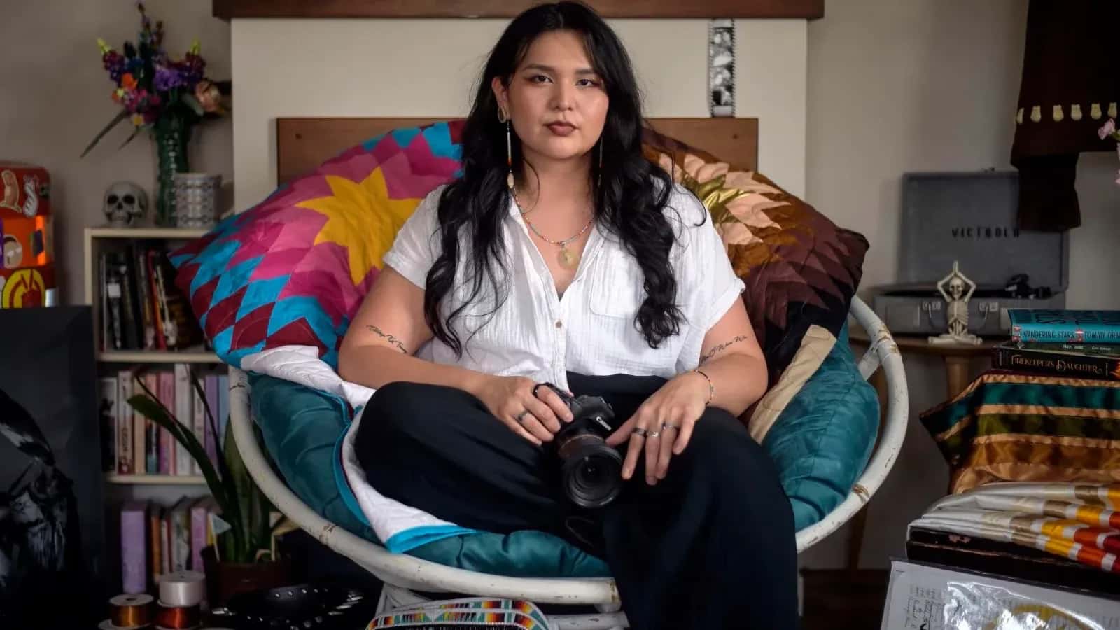 Eunice Straight Head sits for a photo inside their apartment in Rapid City with a variety of artwork pieces they've created. (photo by Matt Gade, Rapid City Journal)