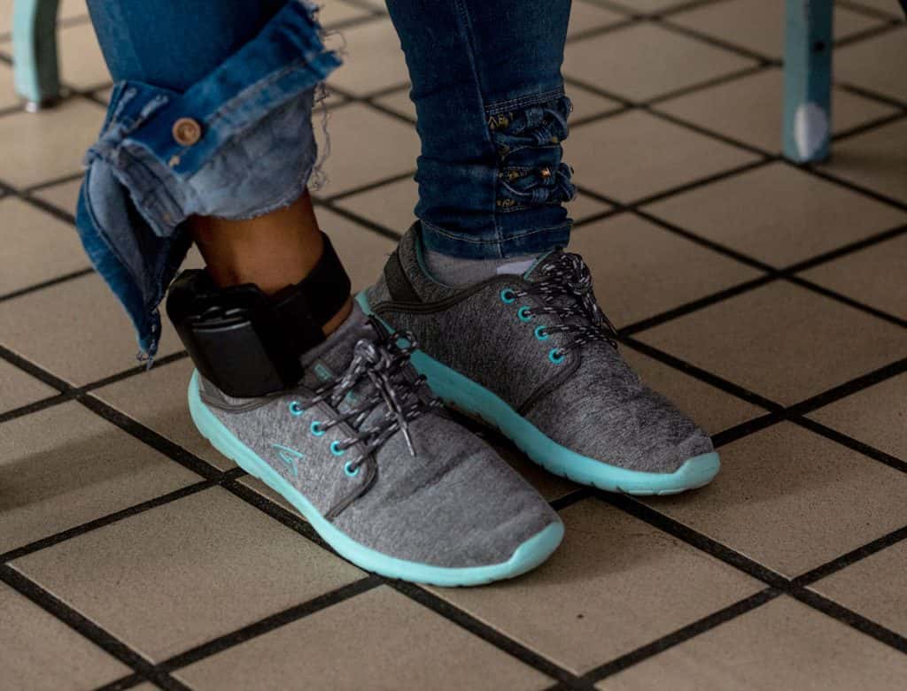 A woman staying at Casa Vides wears an ankle monitor and in the dining area drinking coffee and eating bread. Residents who have been detained by ICE wear ankle monitors as they await their immigration hearings. (Photo: Pablo De La Hoya/Youth Radio)