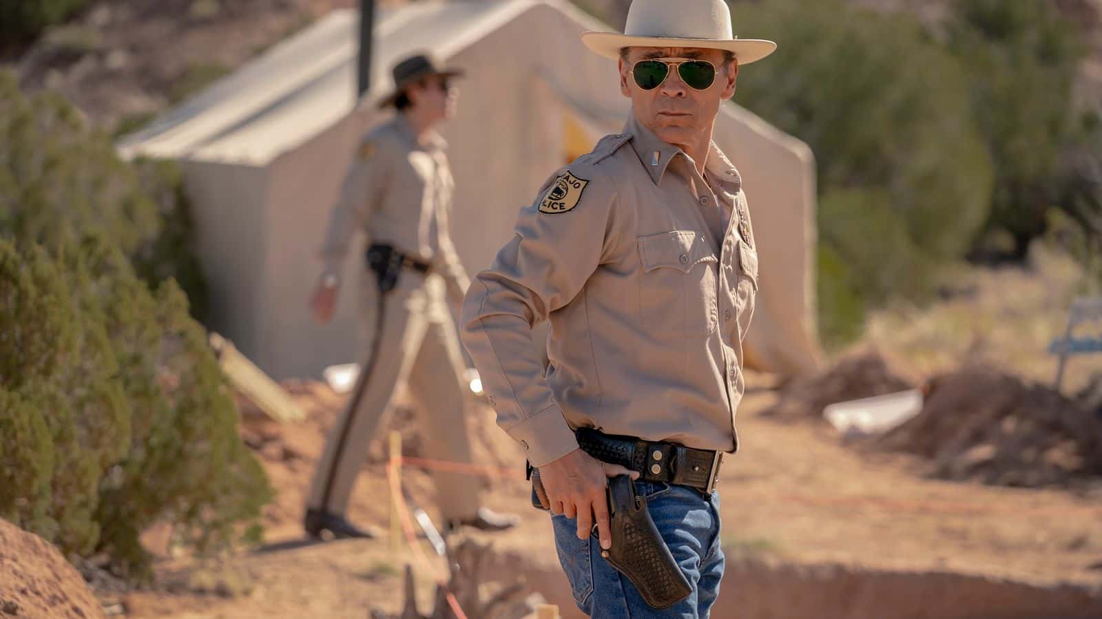 Navajo Police officers Jim Chee (Kiowa Gordon, background) and Joe Leaphorn (Zahn McClarnon) investigate the disappearance of two young Navajo boys in the Season 3 premiere of “Dark Winds.” / Photo credit: AMC
