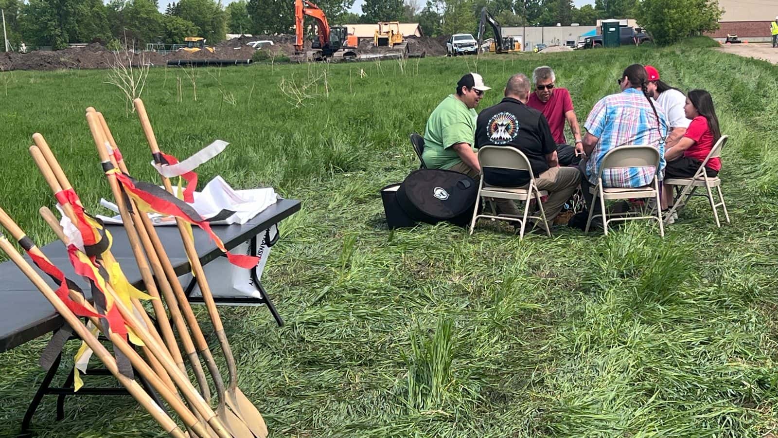 As a sign of community cohesiveness, a drum group opened the groundbreaking ceremony on Friday, May 30, 2025, for the White Earth Transit Station. In the background, heavy equipment operators were busy clearing the ground to begin building construction. / Photo credit: Jodi Spotted Bear