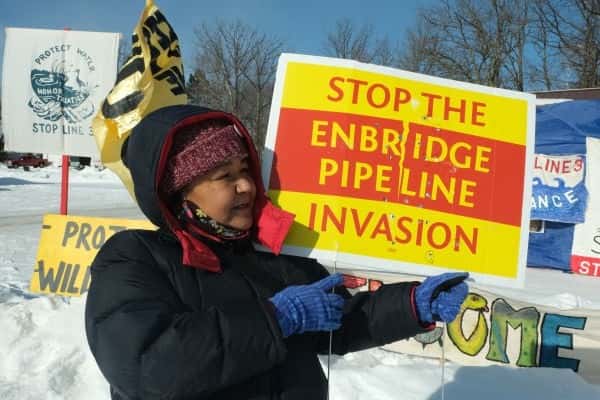 Tania Aubid of the Milles Band of Ojibwe holds a bullet-riddled sign opposing the Enbridge Line 3 project in February 2021. The sign had been in front of her home. (Photo by Mary Annette Pember, Indian Country Today)