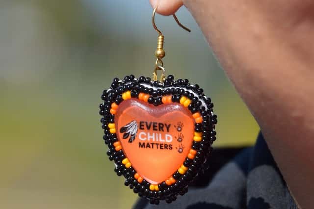 Heather George wears a pair of earrings with the slogan "Every Child Matters" while marching with Mohawk Institute survivors and their families for access to Anglican Church records. Photo by Celia Clarke, NCPR