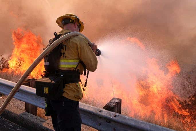 A firefighter battles a fire along the Ronald Reagan (118) Freeway in Simi Valley, Calif., Monday, Nov. 12, 2018. (AP Photo/Ringo H.W. Chiu).