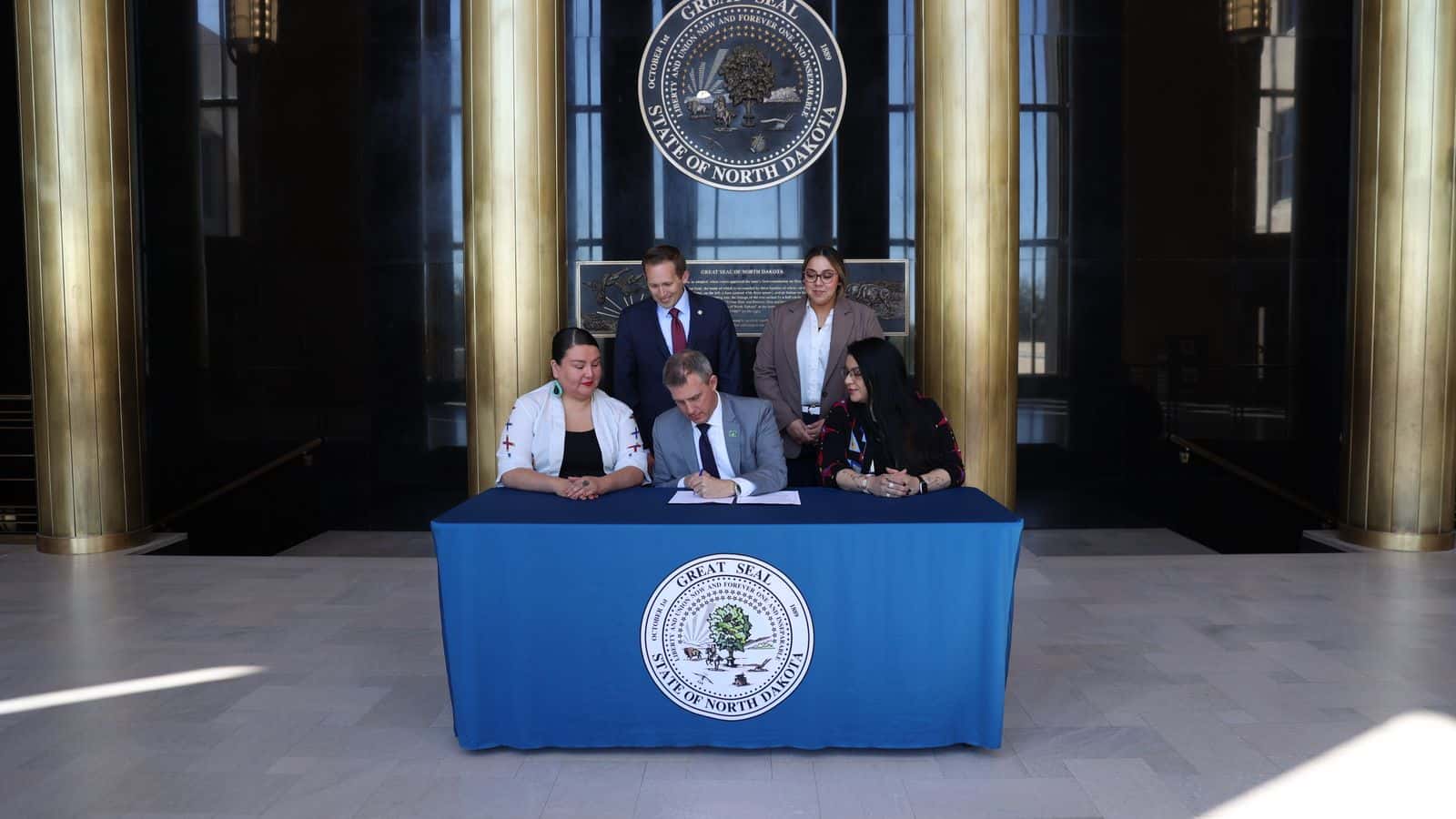 North Dakota Governor Kelly Armstrong signs HB 1535 into law on May 2, flanked by the bill’s sponsor, state. Rep. Jayme Davis on the left, and state Rep. Colette Brown on the right. Behind them are House Minority Leader Zach Ista and House Minority Office Assistant Shayla Davis. (Photo credit: North Dakota’s Governor’s Office)
