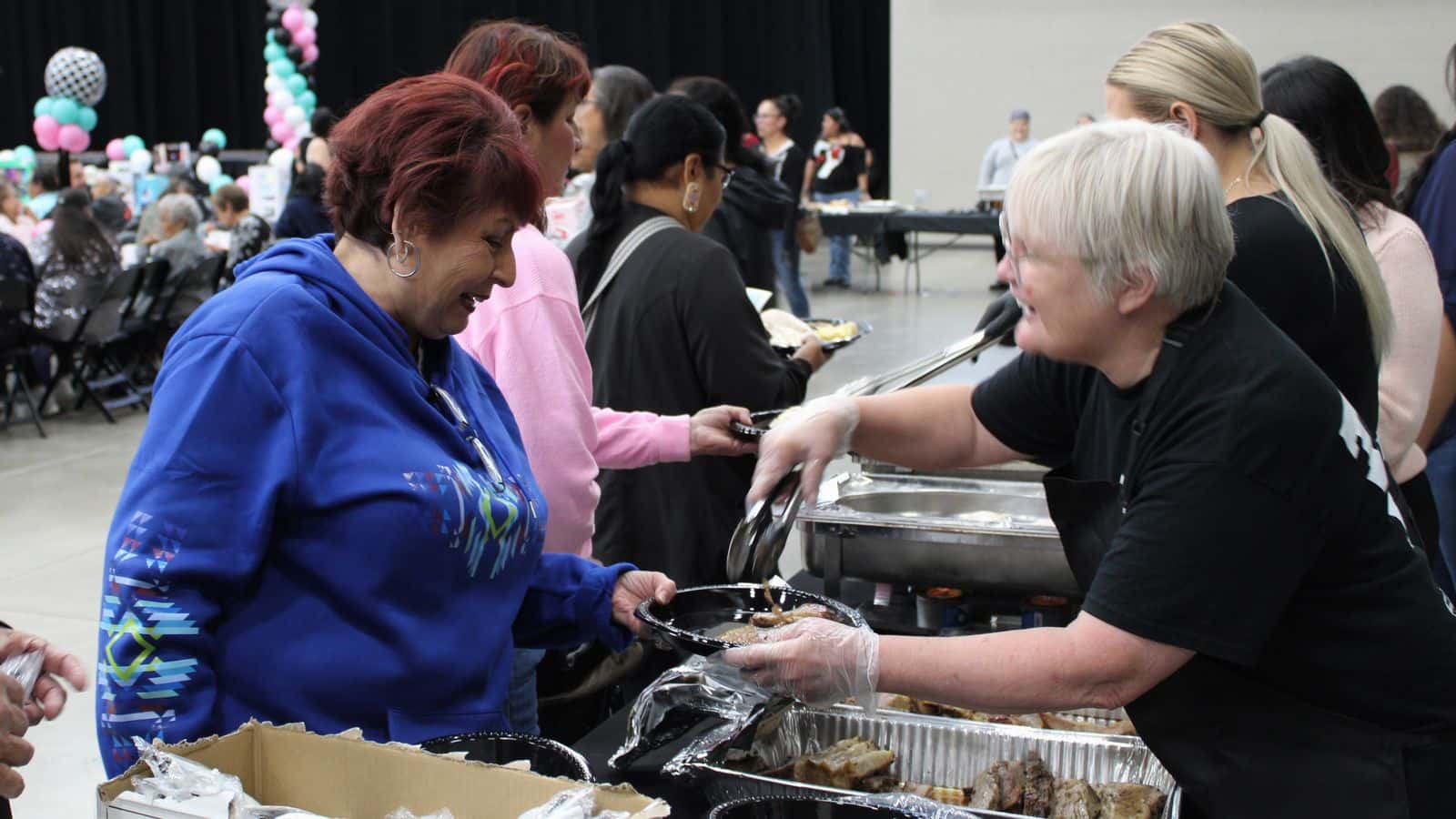 Elders line up to eat barbecue brisket, chicken, cheesy potatoes, corn and cake at the 4 Bears Casino Event Center, July 16.
