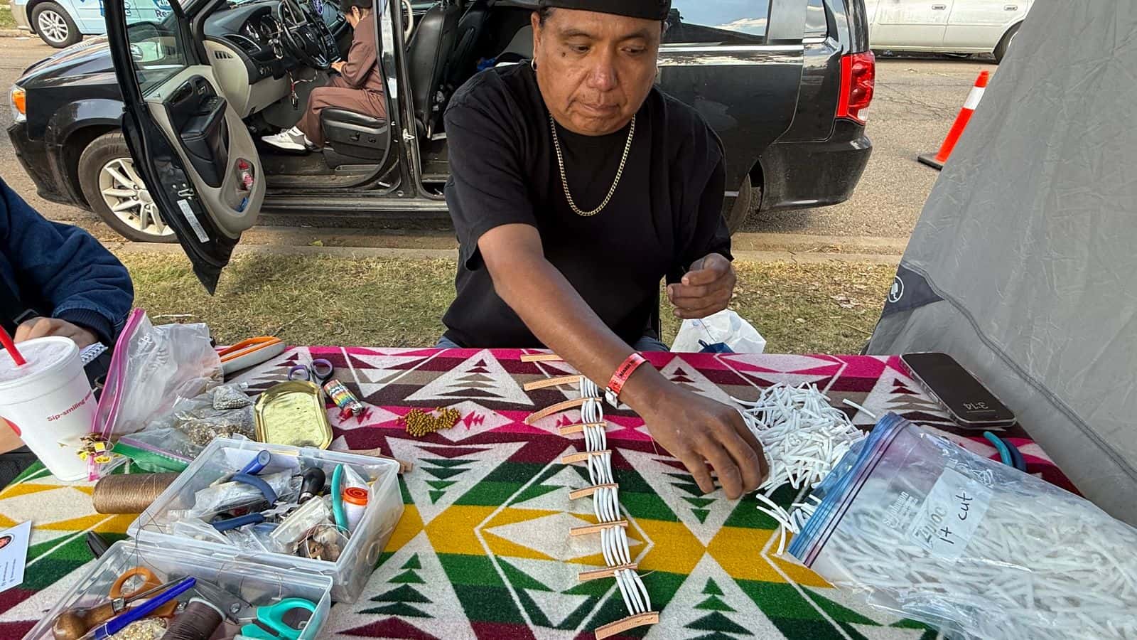Russell McCloud makes a dentalium necklace at the UTTC International Powwow, Bismarck, North Dakota, Saturday, Sept. 6, 2025. He also creates dentalium breastplates, earrings and bracelets under the brand Russwear. (Buffalo’s Fire/Jodi Rave Spotted Bear)