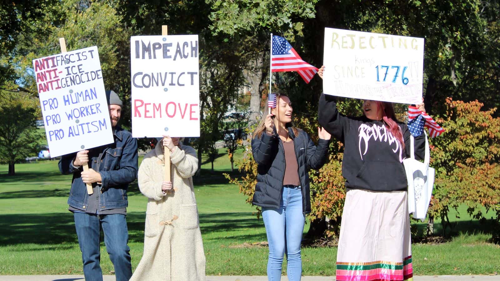 Selena Silk (Standing Rock) and Picabo Reeves (MHA and Standing Rock) hold American flags, standing with other protesters in front of the North Dakota State Capitol at the “No Kings” rally. Reeves held a sign that read, “Rejecting kings since 1776! Honor the Treaties,” Bismarck, North Dakota, Saturday, Oct. 18, 2025. (Buffalo’s Fire/Gabrielle Nelson)