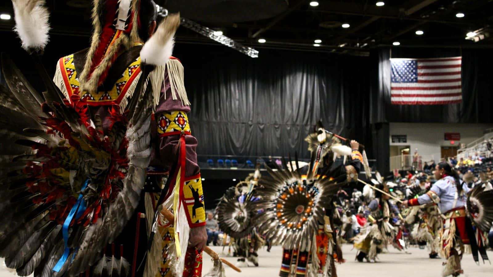 Powwow dancer on deck watches others competing, Bismarck Event Center, North Dakota