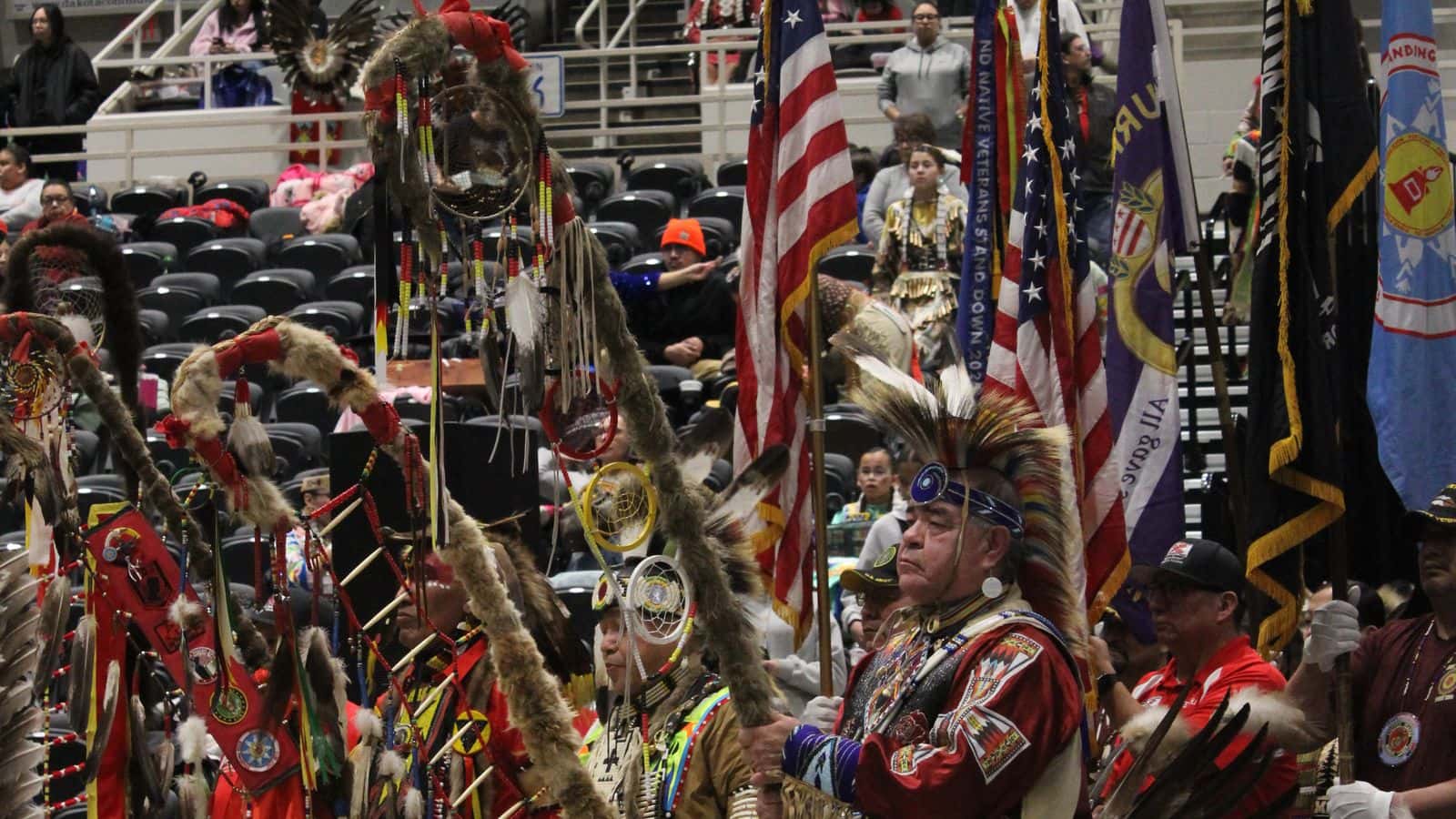 Dancers representing Great Plains tribal nations and flag bearers wait for the start of the drumbeat to begin the first grand entry procession, Bismarck Event Center, North Dakota