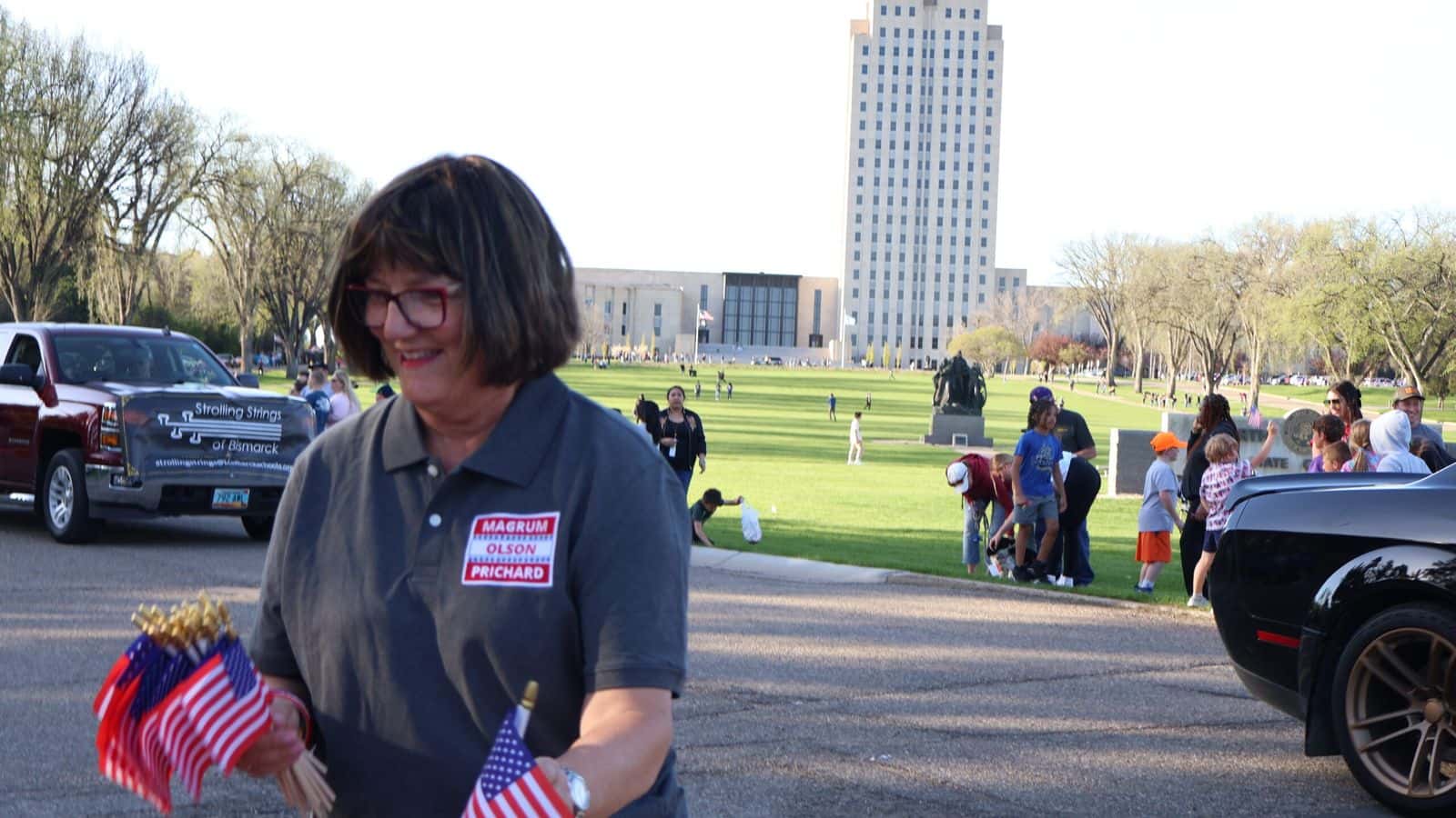 Rep. SuAnn Olson, R-Wilton, hands out flags May 10, 2024, during the Band Night parade in Bismarck. (Amy Dalrymple/North Dakota Monitor)