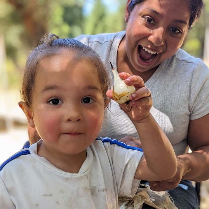 Two-year-old Ira Witcraft holds up a peeled camas bulb as his mother, LeeAndria Witcraft, marvels at the sight, July 19. (Photo credit: Margaret Bull)

