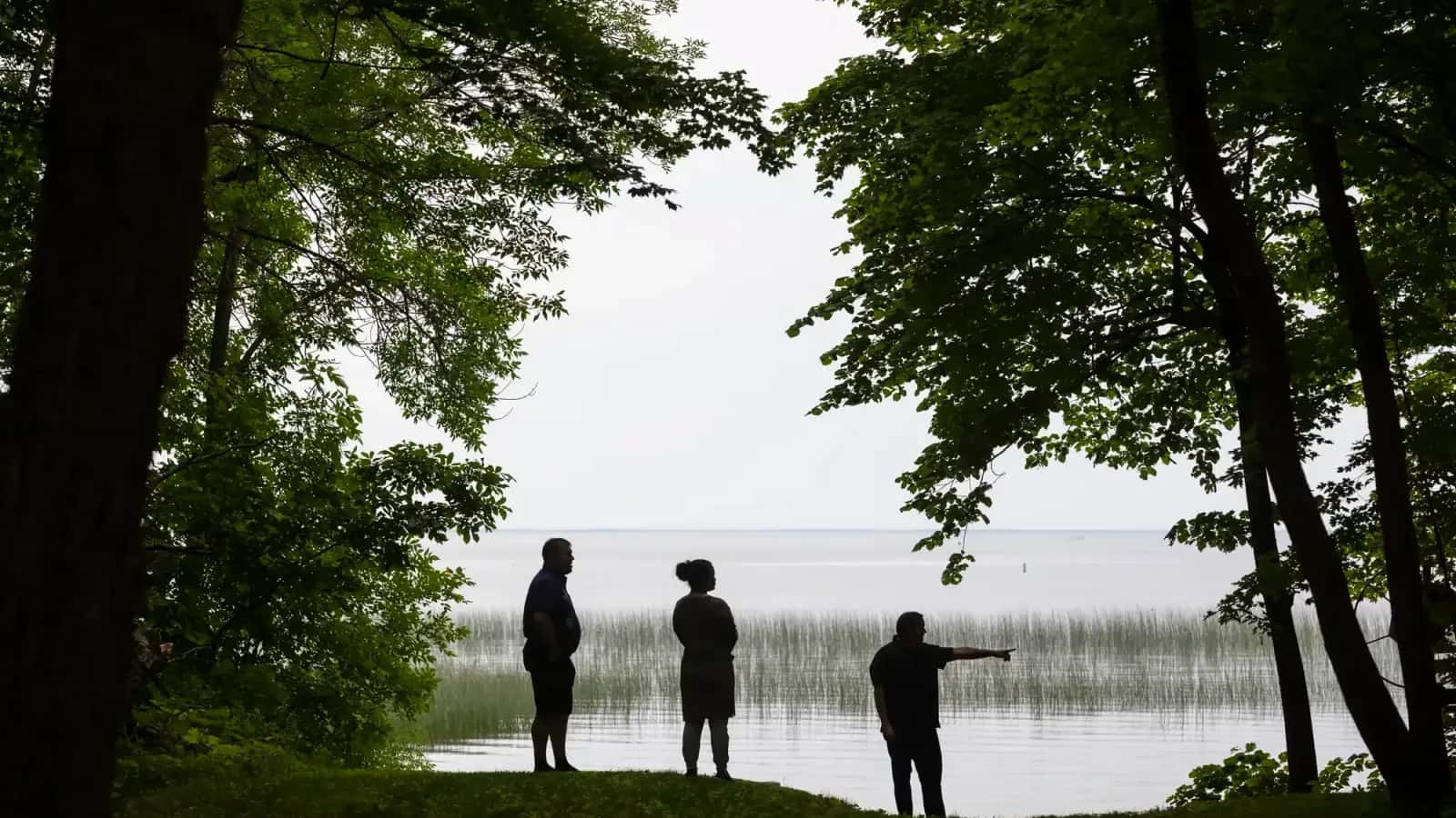 Mille Lacs Band of Ojibwe District 1 Representative Virgil Wind, Deanna Wilson Fredrickson and Commissioner of Natural Resources Kelly Applegate look out over Mille Lacs Lake from Band elder Dixie Kamimura’s home in Onamia, Minnesota on June 24. (Liam James Doyle for MPR News)