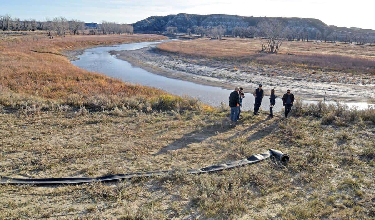 A flexible hose lies next to the Little Missouri River as oil company representatives tour the area in 2017. The hose is used in the process of sourcing water from the river for use by the oil industry for hydraulic fracturing in western North Dakota. - Tom Stromme