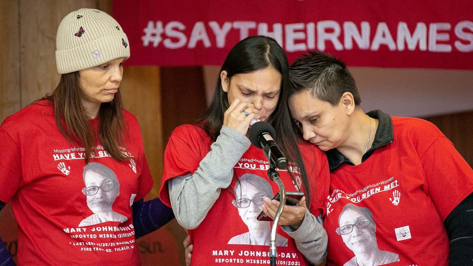 Gerry Davis, supported by sisters Sara, left, and Nona Blouin, reads a statement asking for help in the search for their missing sister, Mary Ellen Johnson-Davis, during a gathering marking two years since her disappearance in Snohomish County on Sunday, Dec. 11, 2022, at Daybreak Star Indian Cultural Center in Seattle, Washington. (Ryan Berry / The Herald)