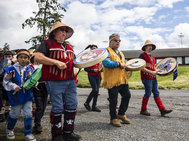 Tulalip drummers and singers make their way down to the water to greet the king salmon as it is carried back to the longhouse during Salmon Ceremony on Saturday, June 11, 2022 in Tulalip, Washington. (Olivia Vanni / The Herald)