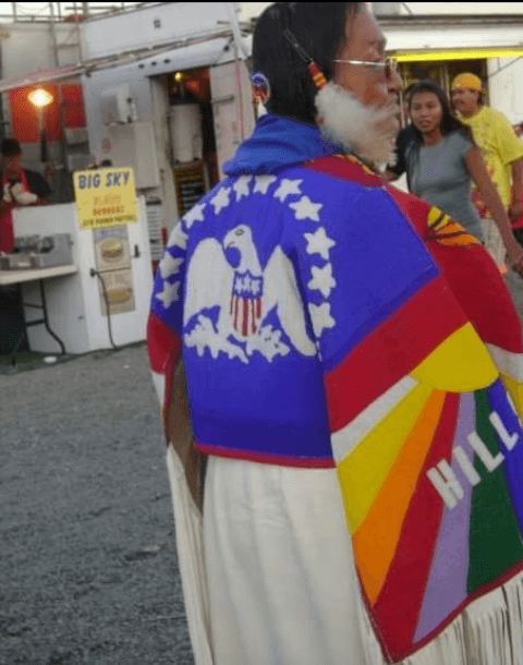 Ernestine Gopher beadced emblem of Indian Peace Flag and the memory of Hill 57 onto her buckskin dress.