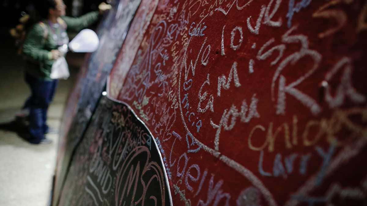 A participant writes on a message board adorned with notes for loved ones who took their own lives during an Out of the Darkness Walk event organized by the Cincinnati Chapter of the American Foundation for Suicide Prevention in Sawyer Point park, Sunday, Oct. 15, 2017. (AP Photo/John Minchillo)