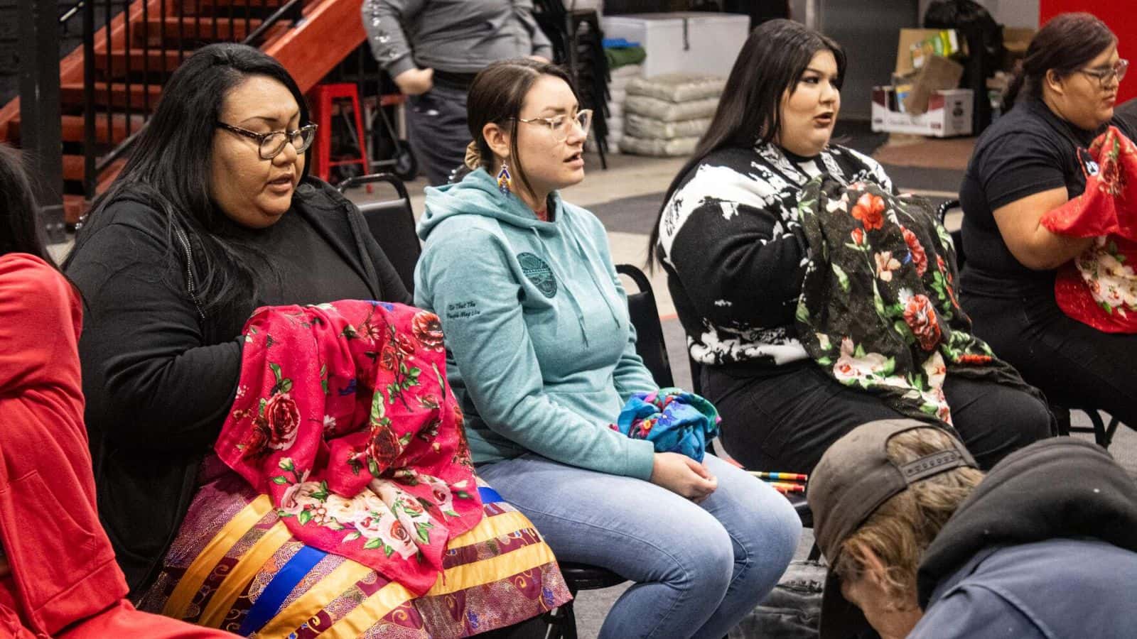A women's team helps a new player learn how to play hand games during a tournament hosted by the Oyate Health Center on Friday, January 19, 2024, in Rapid City, South Dakota. (Photo by Amelia Schafer, ICT/Rapid City Journal)