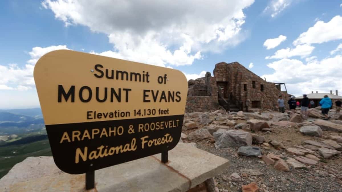 Visitors pass the sign on the summit of Mount Evans near Idaho Springs, Colo., on July 15, 2016. A Colorado state panel changed the mountain’s name on Friday, Sept. 15, 2023, to Mount Blue Sky. (AP Photo/David Zalubowski, File)