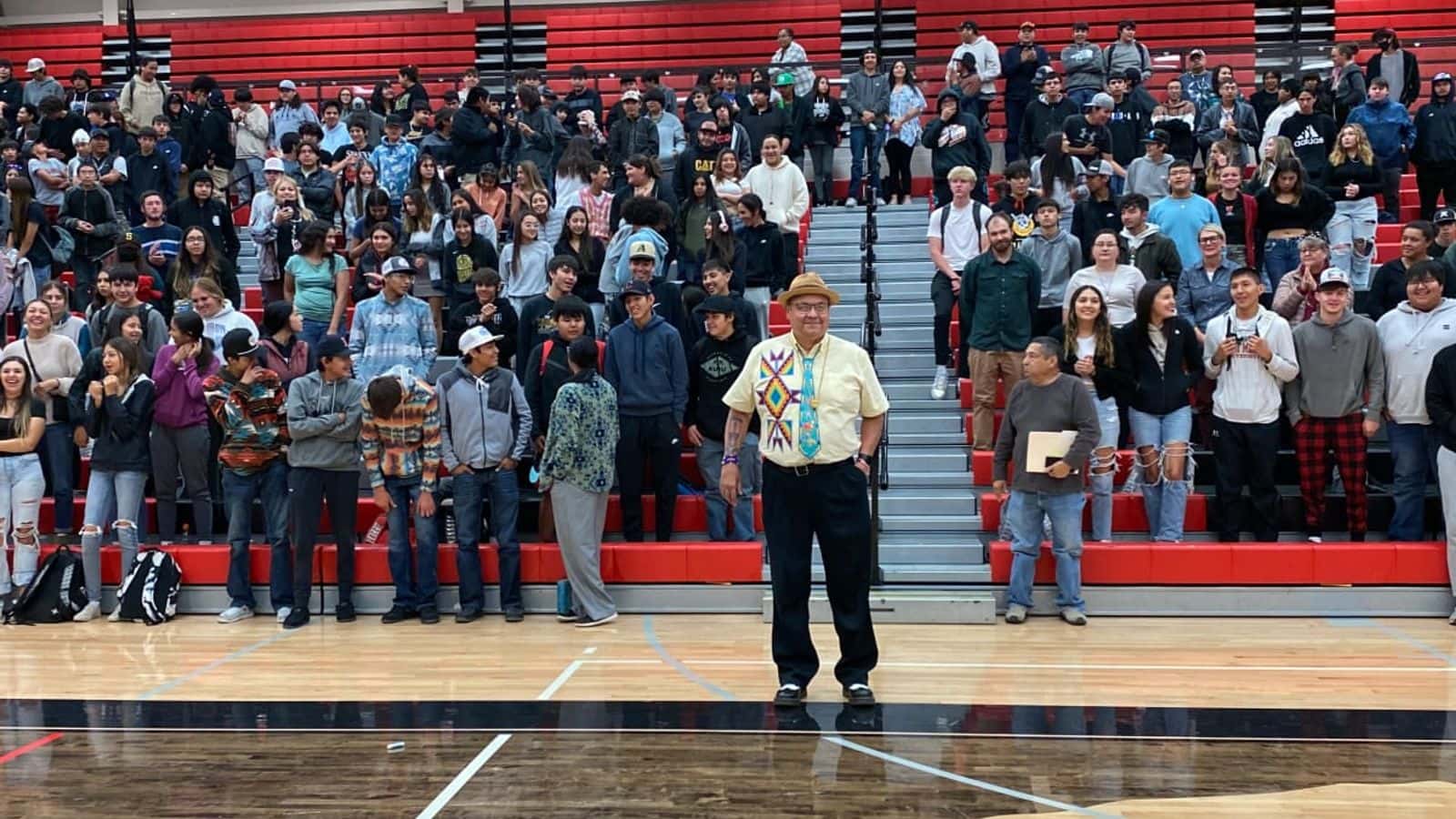 The 2024 Montana Teacher of the Year, Kevin Kicking Woman, stands in front of the Browning High School student body during the award assembly on Sept. 28, 2023, in Browning, Montana. (Photo by Kolby Kicking Woman, ICT)