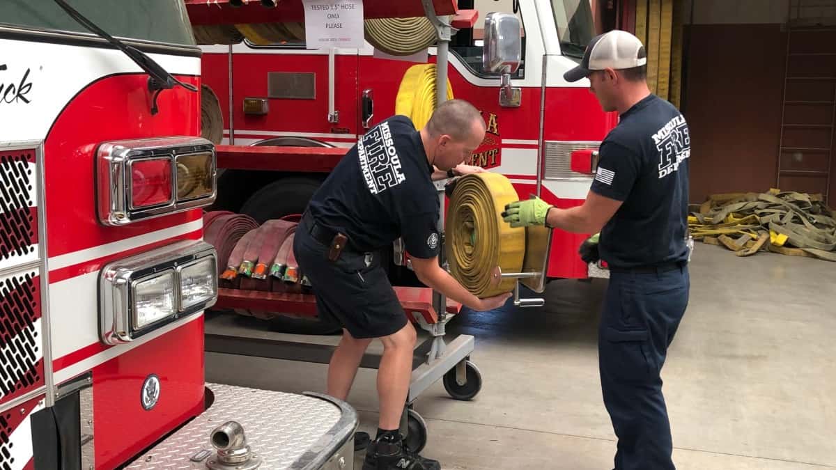Missoula Fire Capt. Ben Webb, left, and firefighter/paramedic Chad Maney coil a hose at the downtown station Wednesday, Sept. 13, 2023. Webb and his crew often respond to calls in the area around Reserve Street north of the Clark Fork River, where the department plans to establish a new company paid for by a $7 million levy on the November ballot. Credit: Katie Fairbanks / MTFP