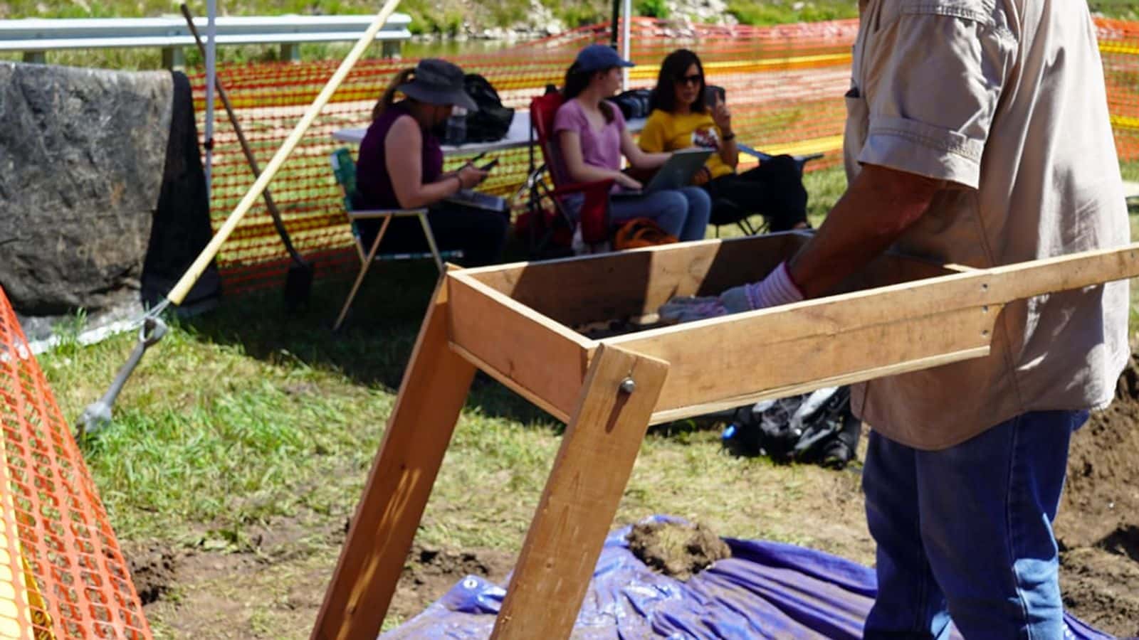 A volunteer for the Nebraska state archaeologist's office sifts through dirt Wednesday, July 12, 2023 taken from a hole being dug at the former Genoa Boarding School, where as many as 80 former students are believed to have been buried. The student cemetery in Genoa, Nebraska was lost following the school's closure in 1934. (Kevin Abourezk, ICT News)