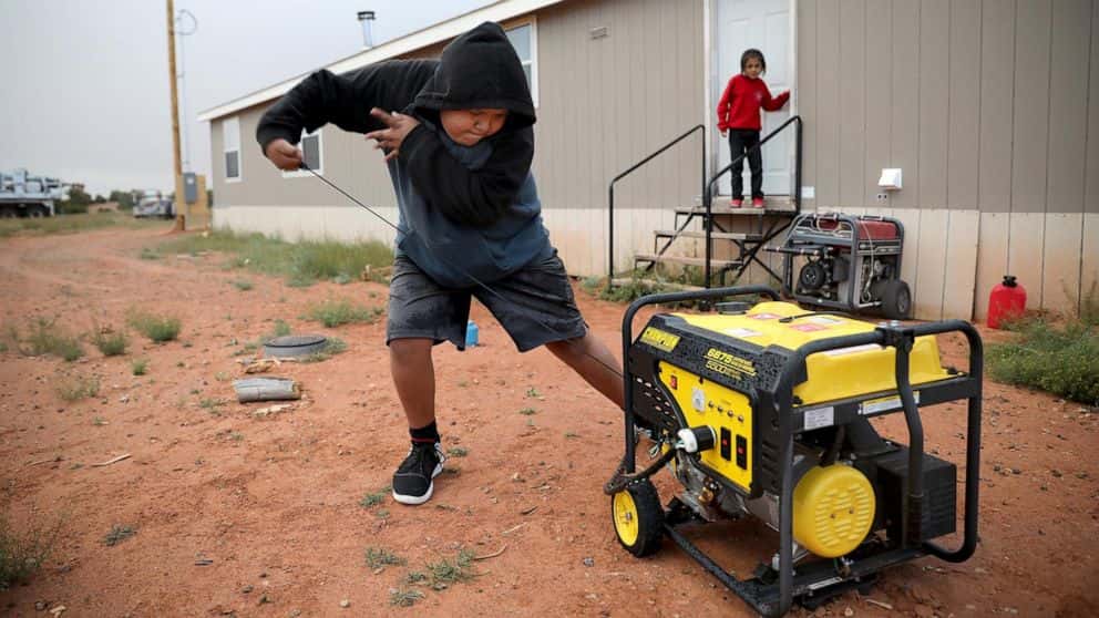 Jayden Long starts the generator behind his Kaibeto home on the Navajo Reservation in Arizona, May 8, 2019, so that he can charge his cell phone inside the family home. The U.S. Interior Department on Tuesday, Aug. 15, 2023, unveiled a new program to bring electricity to more homes in Native American communities as the Biden administration looks to funnel more money toward climate and renewable energy projects. (AP Photo, Jake Bacon)