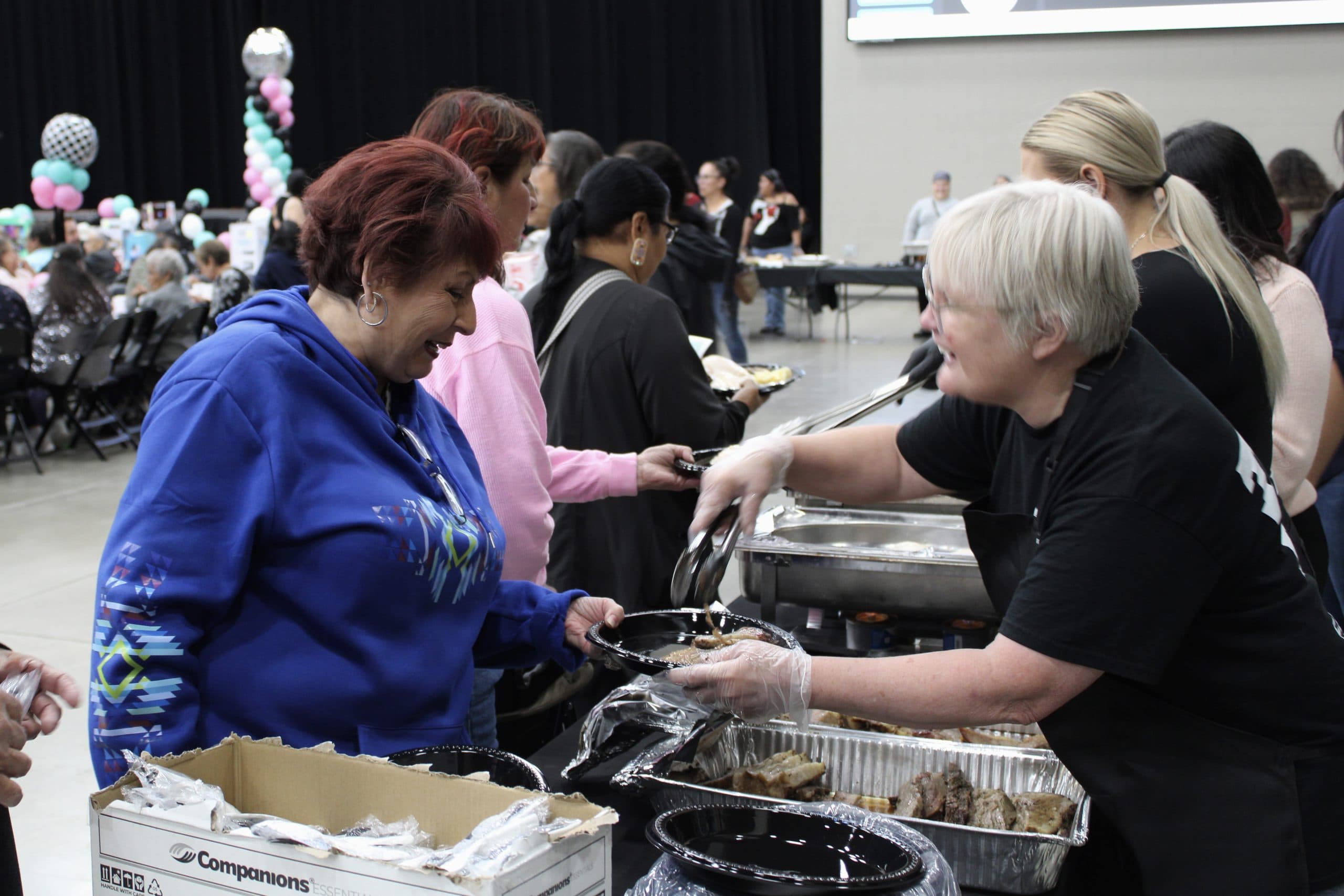 Elders line up to eat barbecue brisket, chicken, cheesy potatoes, corn and cake at the 4 Bears Casino Event Center, July 16.