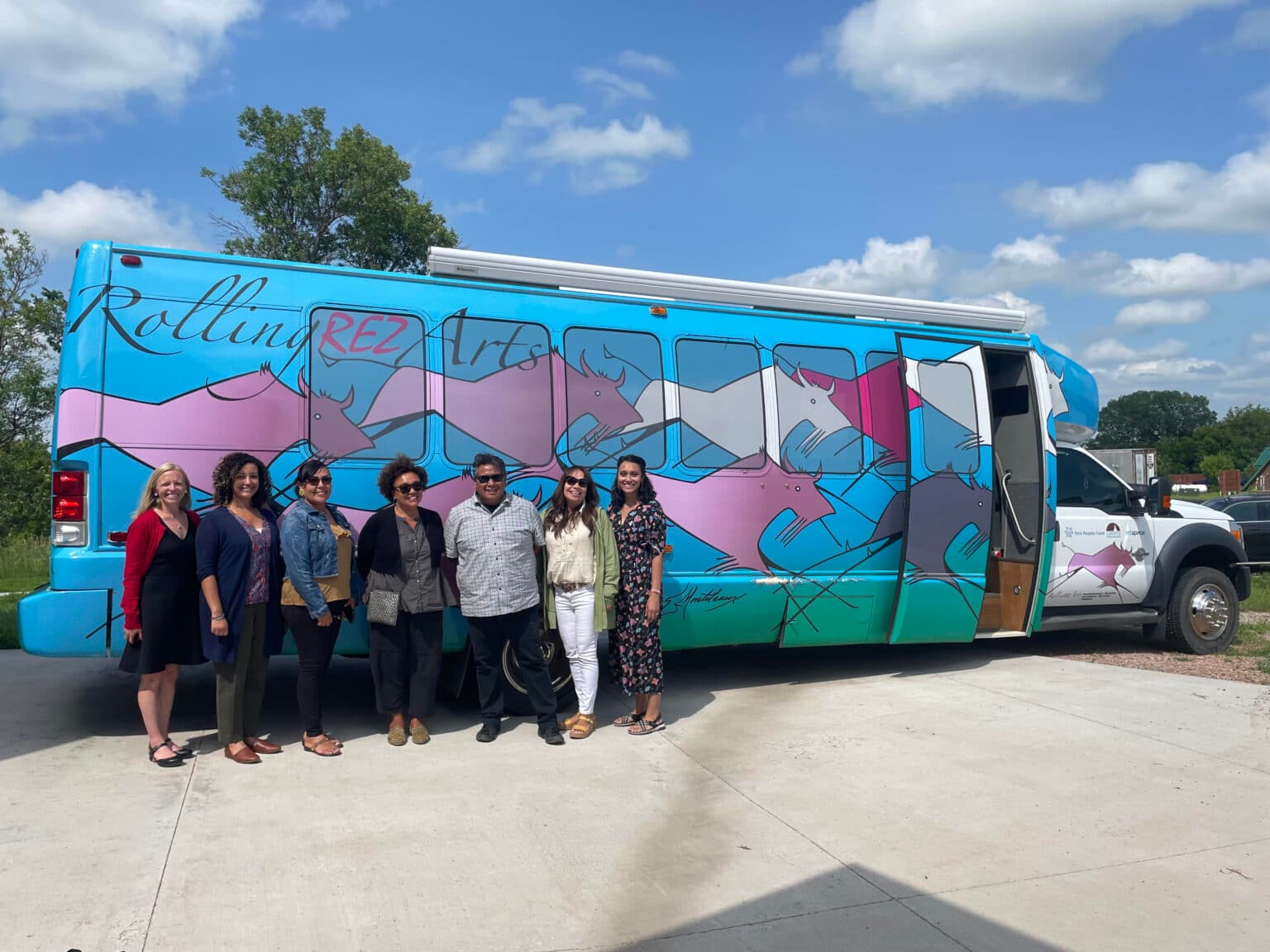 Lori Pourier stands in front of the Rolling Rez Arts Bus (second from right), along with visitors from the National Endowment for the Arts, July 2023.