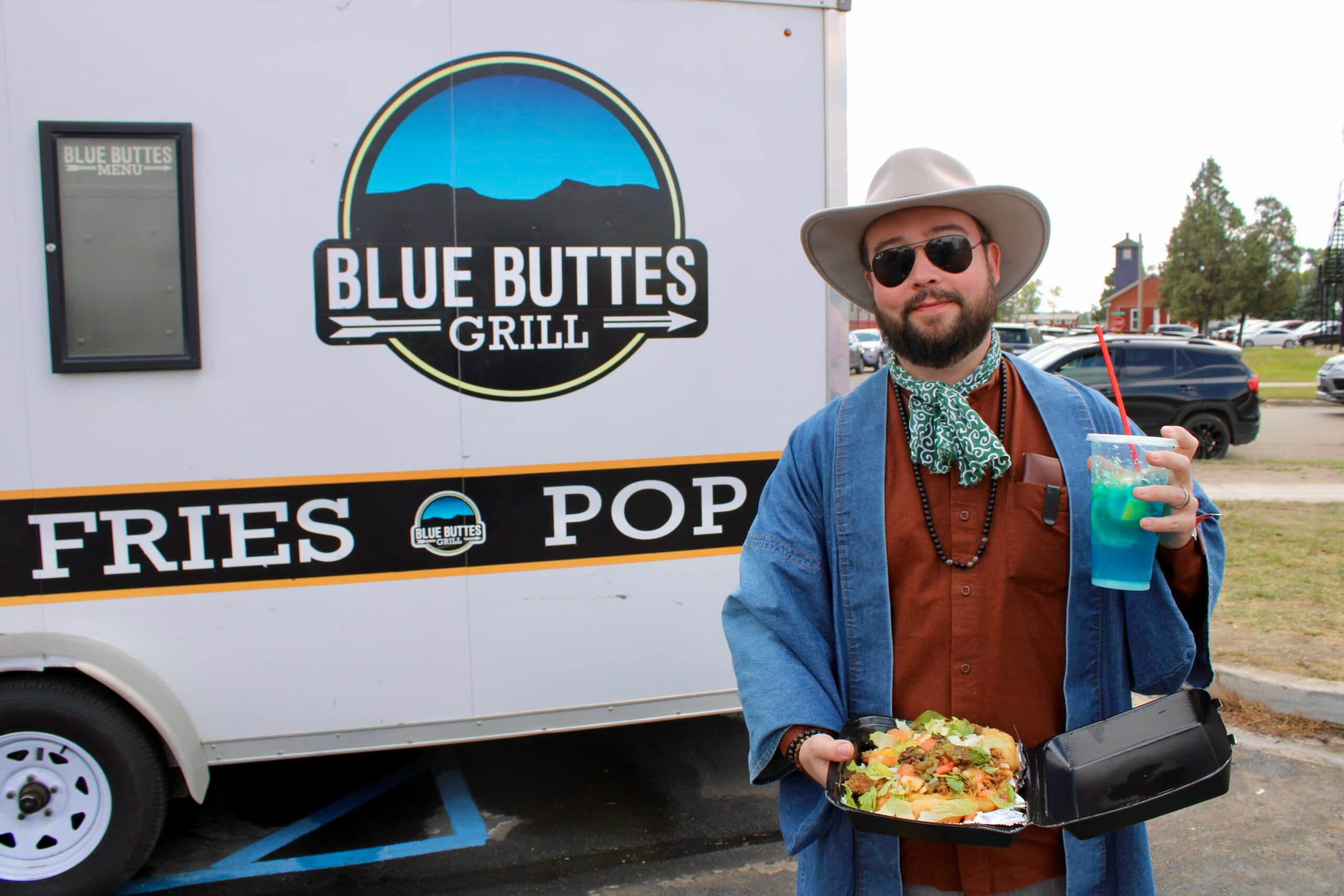 Powwow attendee Rob Buscher stands with an Indian taco from Blue Buttes Grill and a blue “rez” berry lemonade from Rez Famous Lemonades, Bismarck, North Dakota, Saturday, Sept. 6, 2025. (Buffalo’s Fire Photo/Gabrielle Nelson)