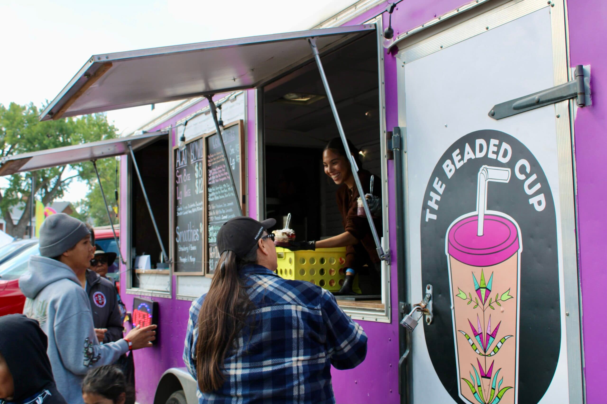 Saydee Archambault, citizen of the Assiniboine Tribe from Fort Belknap, gives a customer an acai bowl, Bismarck, North Dakota, Saturday, Sept. 6, 2025. This was the Beaded Cup’s debut at the UTTC International Powwow.