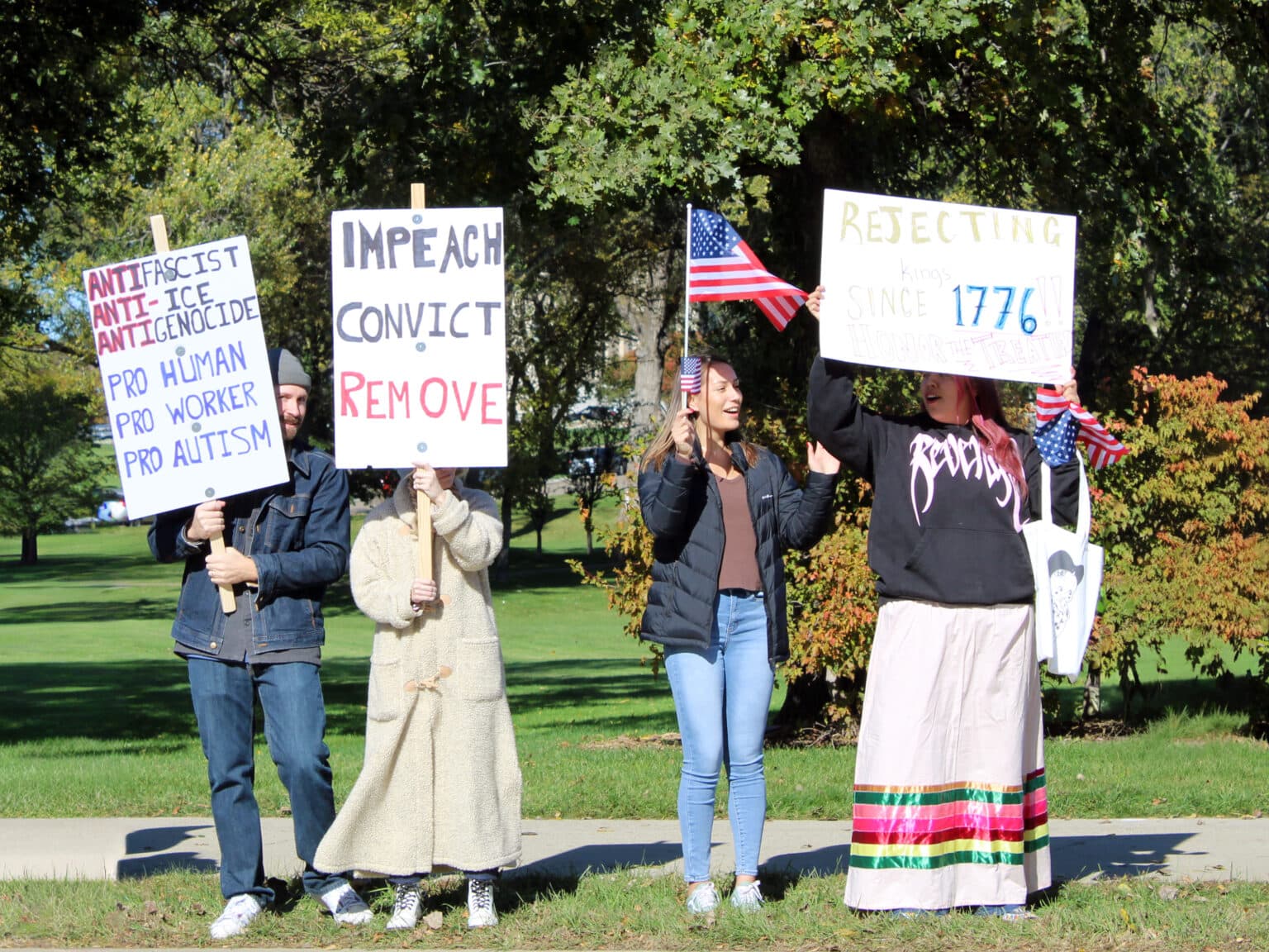 Selena Silk (Standing Rock) and Picabo Reeves (MHA and Standing Rock) hold American flags, standing with other protesters in front of the North Dakota State Capitol at the “No Kings” rally. Reeves held a sign that read, “Rejecting kings since 1776! Honor the Treaties,” Bismarck, North Dakota, Saturday, Oct. 18, 2025. (Buffalo’s Fire/Gabrielle Nelson)