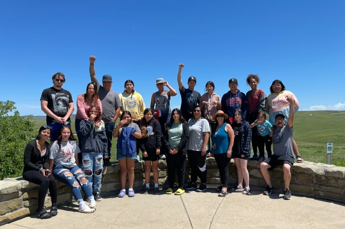 The Defenders of the Water students stand with their instructors, some raising their fists as a symbol of Native solidarity, Little Bighorn Battlefield National Monument, Montana, June 2023.