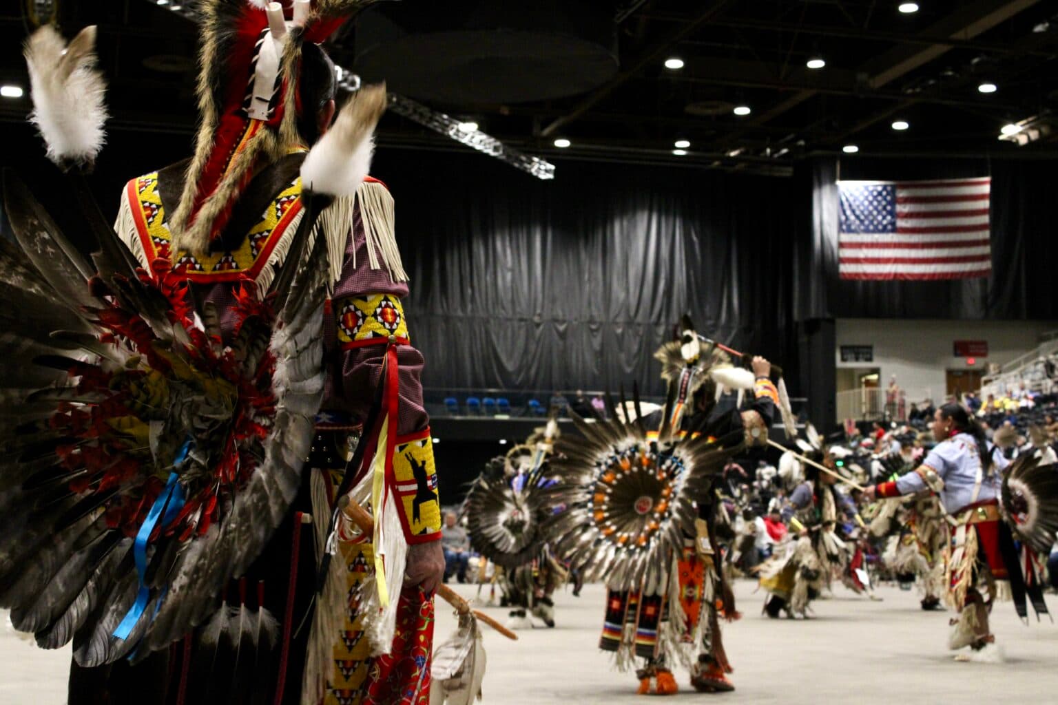 Powwow dancer on deck watches others competing, Bismarck Event Center, North Dakota