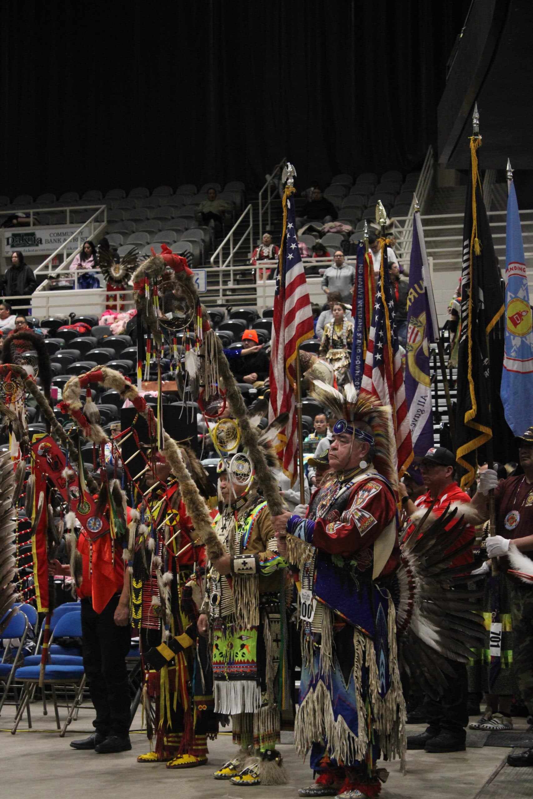 Dancers representing Great Plains tribal nations and flag bearers wait for the start of the drumbeat to begin the first grand entry procession, Bismarck Event Center, North Dakota
