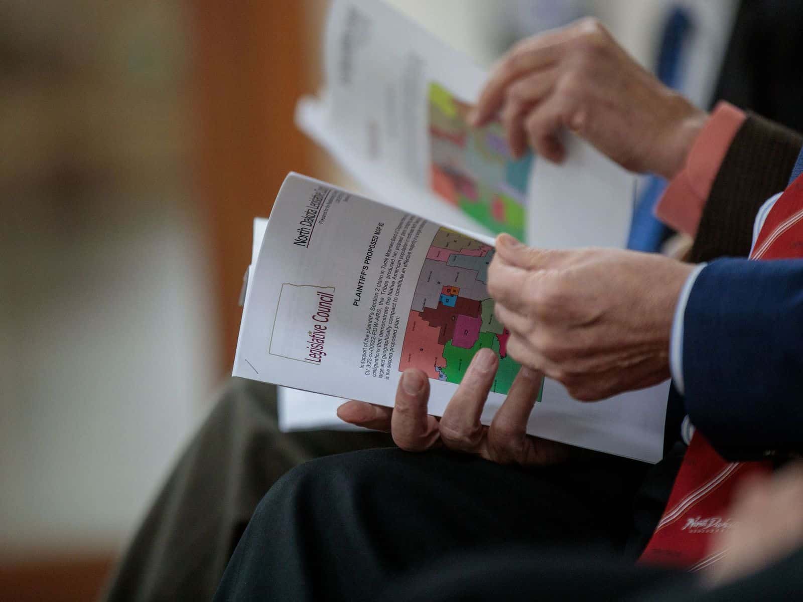 Legislators attending a Redistricting Committee meeting Dec. 13, 2023, look at maps of different proposals.