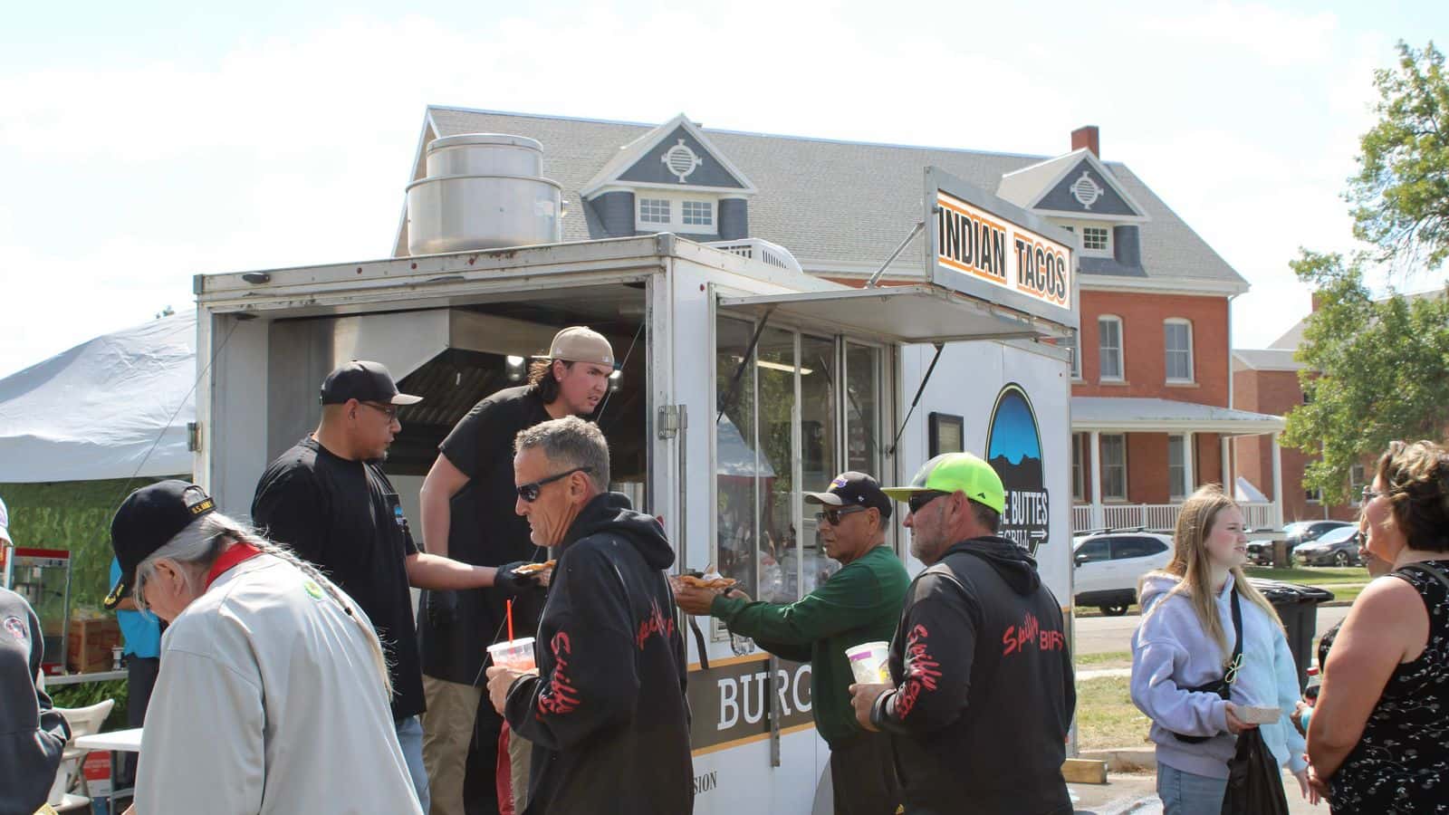 Blue Buttes Grill cook Jordan Davis (in tan hat) hands frybread to a customer while other powwow attendees wait for their food, Bismarck, North Dakota, Saturday, Sept. 6, 2025. (Buffalo’s Fire Photo/Gabrielle Nelson)