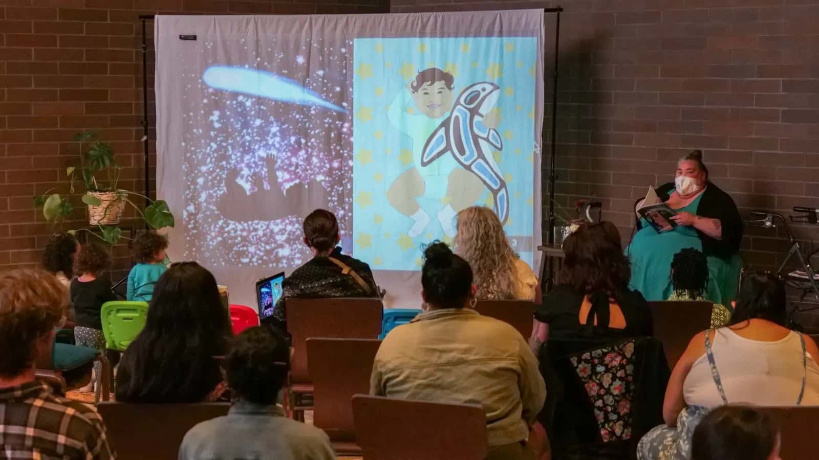 While performing the reading of "Cosmo, From the Stars," Shilo George, Southern Cheyenne and Arapaho descent, asks thoughtful questions to the audience about their experiences and feelings in relation to the book on Sept. 14, 2024 at Barbie's Village. (Photo by Jarrette Werk Underscore Native News / Report for America)
