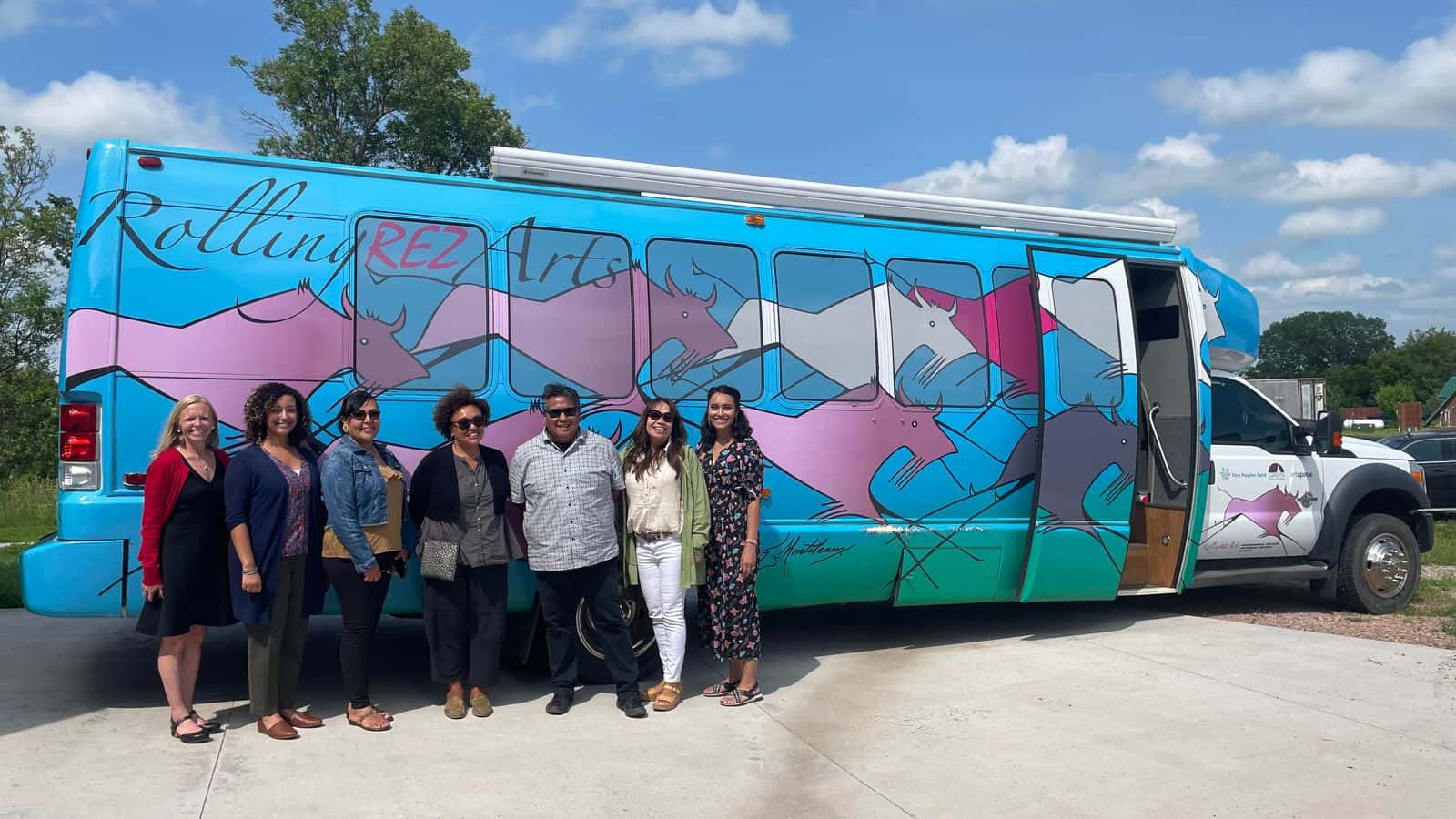 Lori Pourier stands in front of the Rolling Rez Arts Bus (second from right), along with visitors from the National Endowment for the Arts, July 2023.