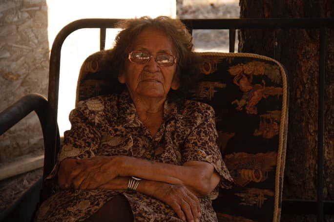 Sally Benally in the shade at her sheep camp. (Photo by Jolene Yazzie)