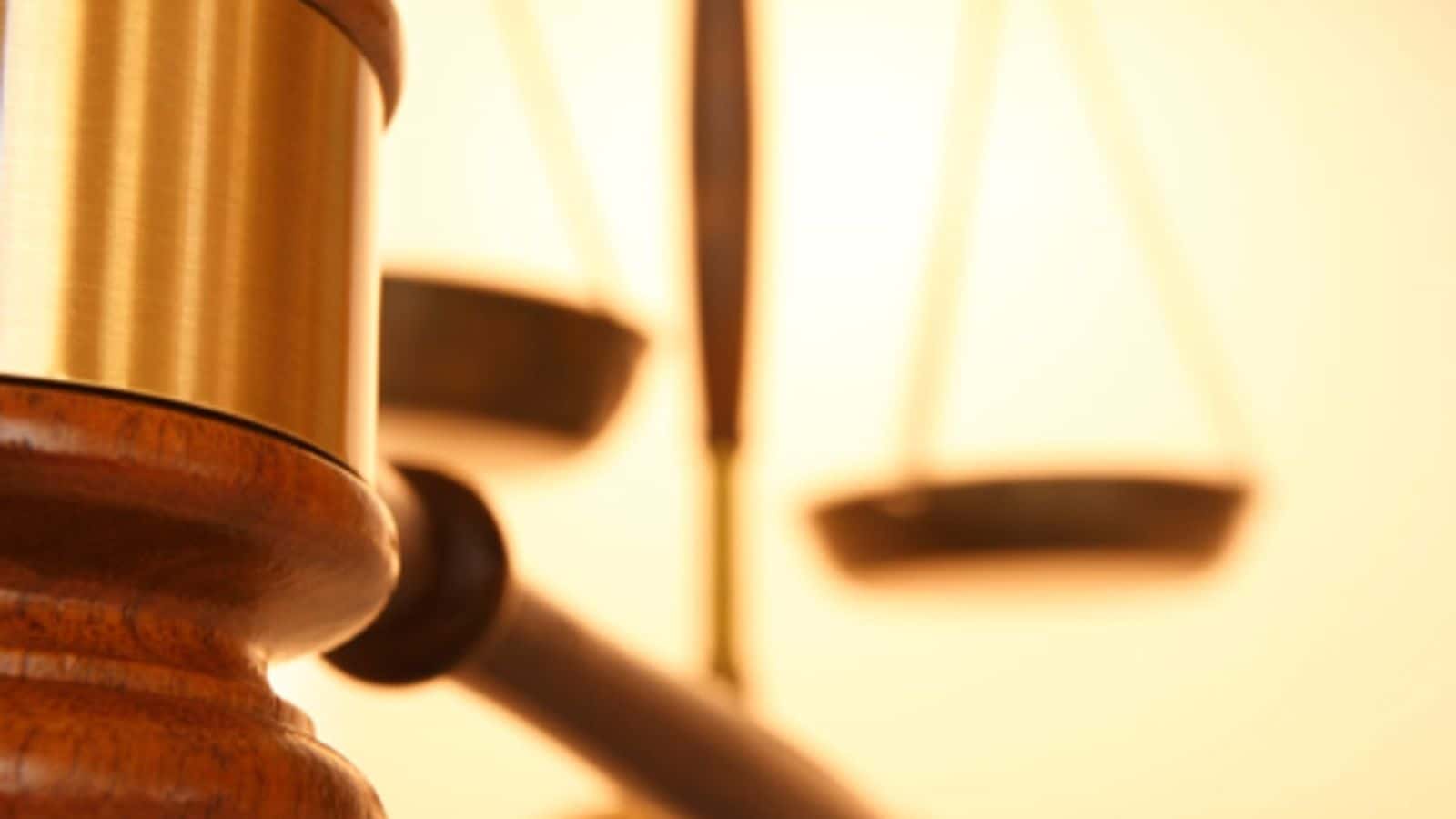 Close up of gavel with justice scale in background - stock photo.