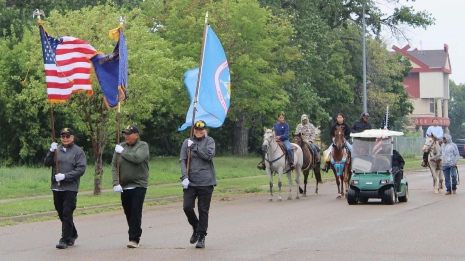 Three veterans lead the 2025 Long Soldier Parade down Standing Rock Avenue in Fort Yates. Five horses and their riders from Horse Nation follow, Saturday, Aug. 2, 2025. (Photo credit: Gabrielle Nelson)