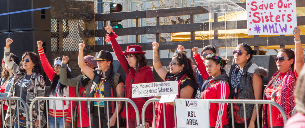 indigenous women protesting missing and murdered native women while holding signs and wearing red