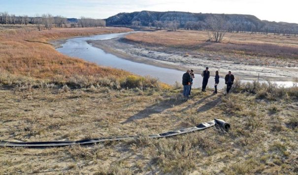 A flexible hose lies next to the Little Missouri River as oil company representatives tour the area in 2017. The hose is used in the process of sourcing water from the river for use by the oil industry for hydraulic fracturing in western North Dakota. - Tom Stromme