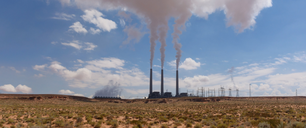 Navajo Generating Station power plant in daytime putting steam into blue sky in distance