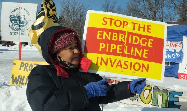 Tania Aubid of the Milles Band of Ojibwe holds a bullet-riddled sign opposing the Enbridge Line 3 project in February 2021. The sign had been in front of her home. (Photo by Mary Annette Pember, Indian Country Today)