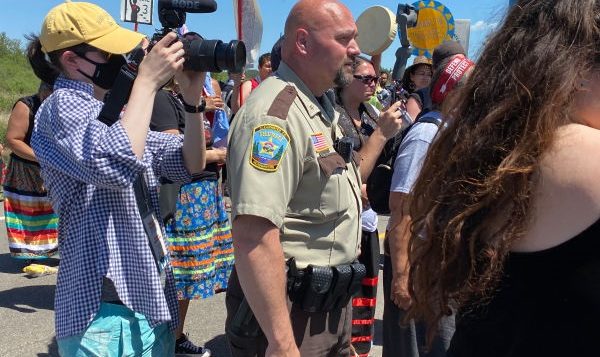 Clearwater County Sheriff Darin Halverson stands with water protectors listening to speakers during a June 7 march to the Mississippi River near an Enbridge Line 3 construction site. Halverson was able to avoid mass arrests that occurred at other protest sites near Solway, Minnesota. (Photo by Mary Annette Pember, Indian Country Today)