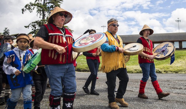 Tulalip drummers and singers make their way down to the water to greet the king salmon as it is carried back to the longhouse during Salmon Ceremony on Saturday, June 11, 2022 in Tulalip, Washington. (Olivia Vanni / The Herald)